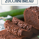 Close up shot of a loaf of the best chocolate zucchini bread sliced on a board with text title box at top