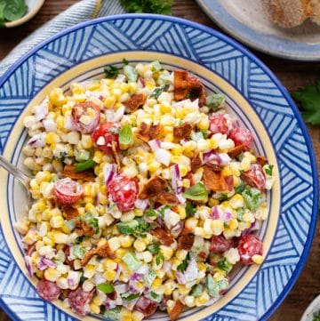 Overhead image of corn tomato salad in a blue bowl with bacon on top