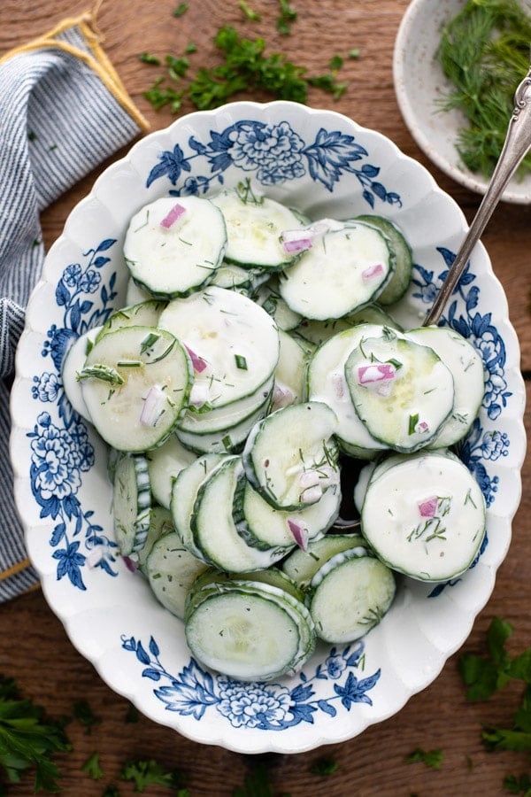 Overhead image of a blue and white bowl full of cucumber and dill salad recipe