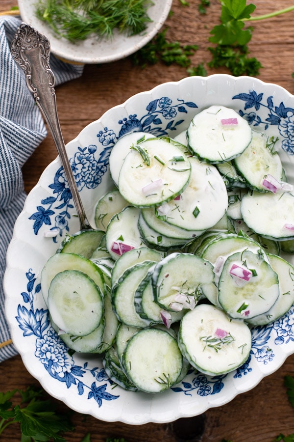 Overhead shot of a bowl of creamy cucumber dill salad on a wooden table