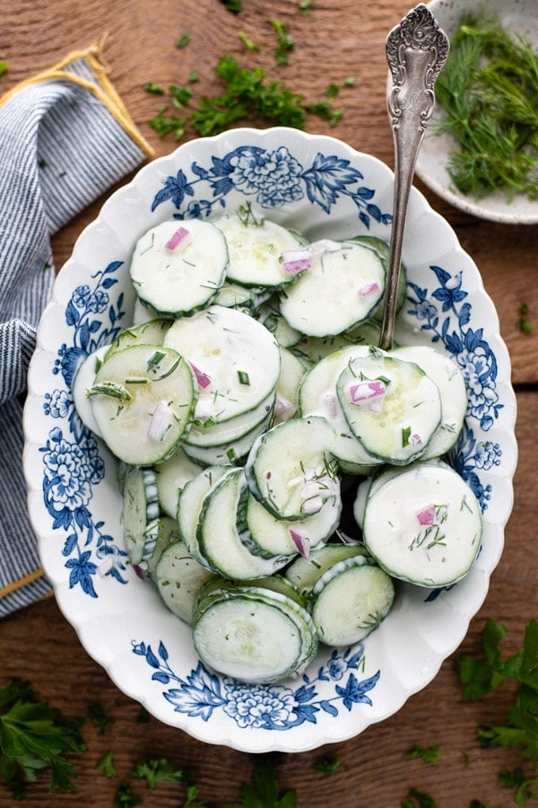 Overhead image of cucumber salad recipe served in a blue and white bowl