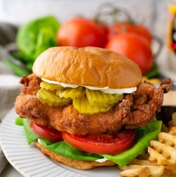 Side shot of a homemade fried chicken sandwich on a plate with fries
