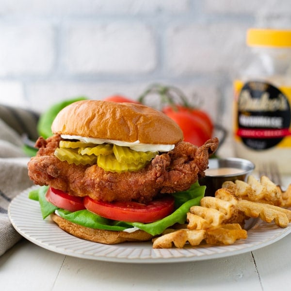 Square image of a Chik Fil A fried chicken sandwich recipe served on a plate with waffle fries