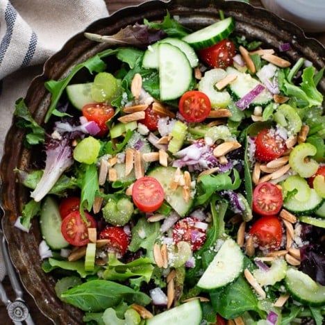 Close overhead shot of a bowl of the best green salad recipe served with homemade vinaigrette dressing