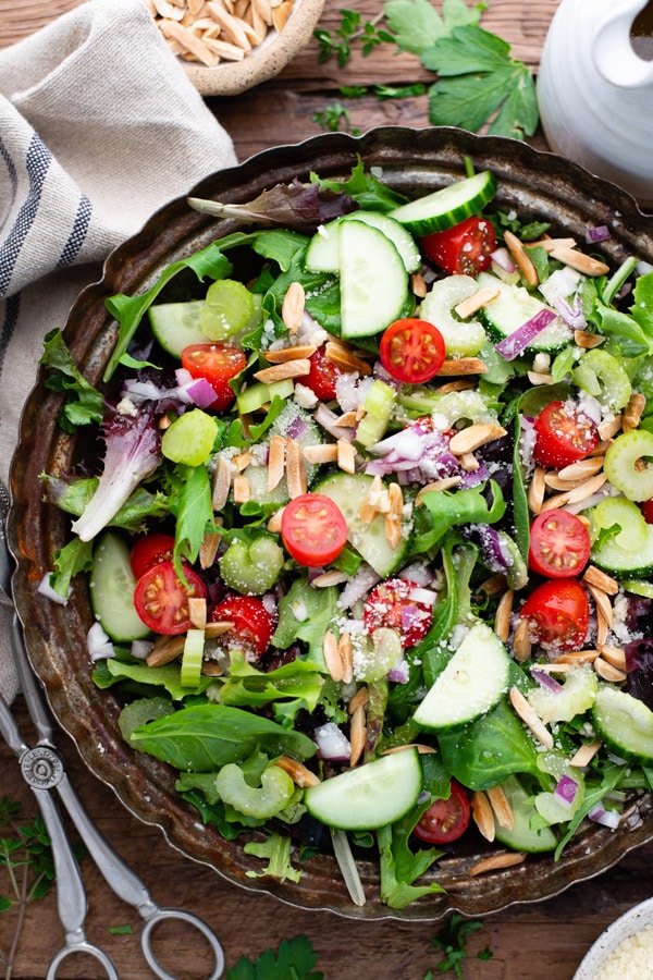 Close overhead image of green salad with vegetables and homemade vinaigrette