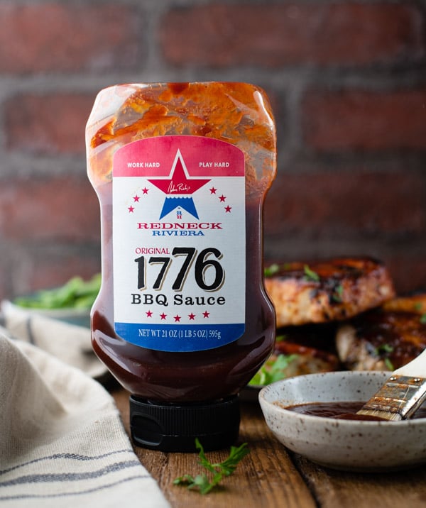 Bottle of 1776 barbecue sauce with grilled pork chops
