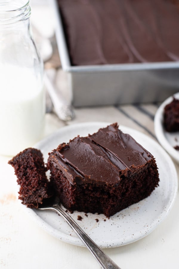 Slice of easy chocolate cake on a white plate with chocolate frosting