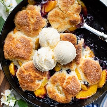 Close overhead shot of peach blueberry cobbler in a cast iron skillet