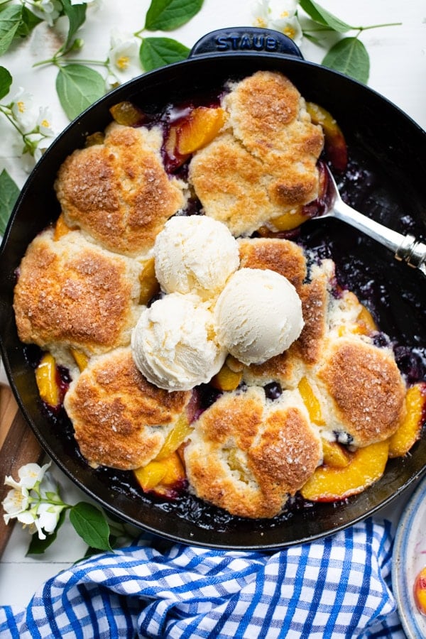 Close overhead shot of peach blueberry cobbler in a cast iron skillet