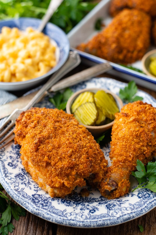 Two pieces of fried Ranch chicken served on a plate. The chicken is coated in a crispy baked breadcrumb coating and served with a small dish of pickles.
