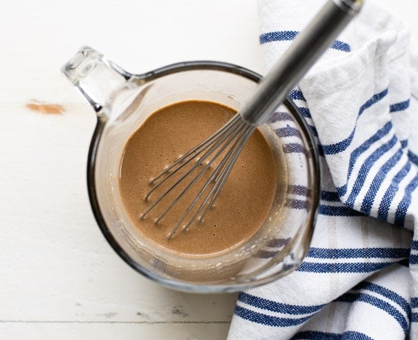 Creamy balsamic vinaigrette dressing in a measuring cup with whisk