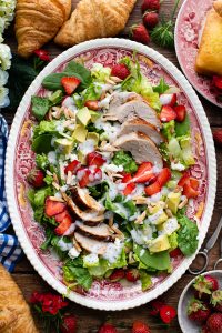 Strawberry poppyseed chicken salad on a wooden table surrounded by croissants