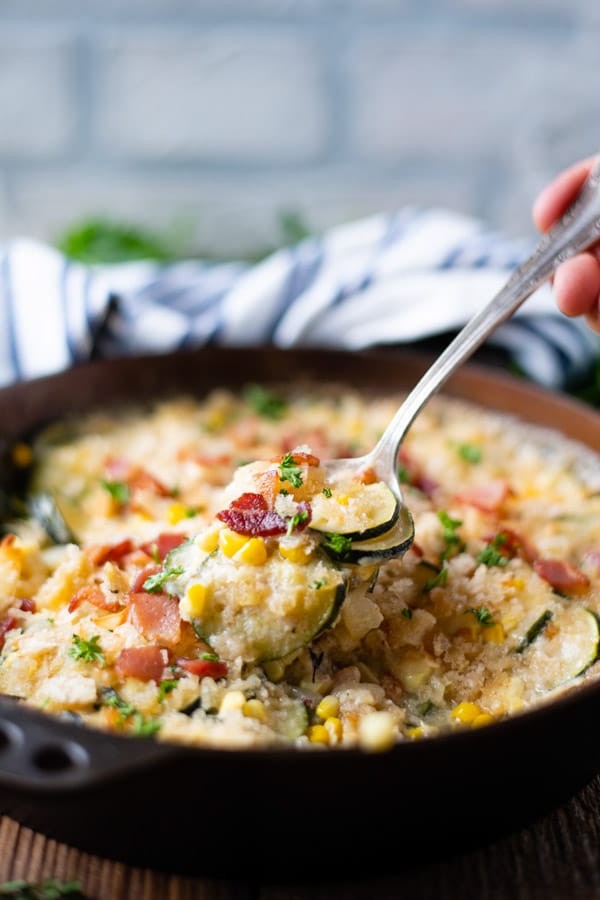 Spoon serving easy zucchini gratin from a skillet