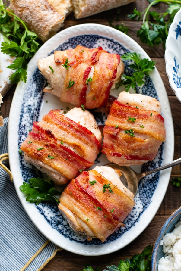 Overhead shot of a blue and white tray full of bacon wrapped stuffed chicken breast