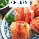 Close up front shot of bacon wrapped chicken breast on a plate with text title overlay