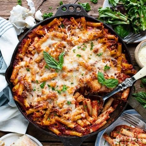 Square overhead shot of baked ziti with sausage in a cast iron skillet.