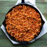 Shredded chicken tossed with pasta and marinara sauce in a cast iron skillet
