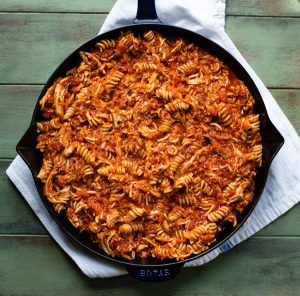 Shredded chicken tossed with pasta and marinara sauce in a cast iron skillet