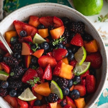 Close overhead image of a bowl of the best fruit salad recipe served in a white handmade bowl
