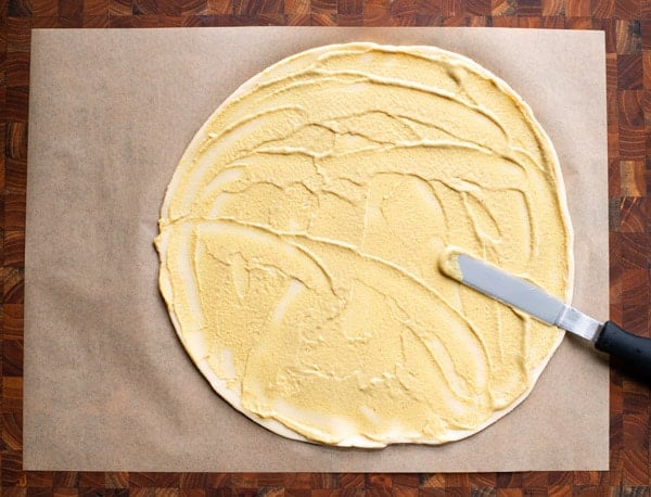 Spreading Dijon mustard on pie crust dough