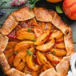 Overhead image of a spiced rustic peach galette on a green wooden table