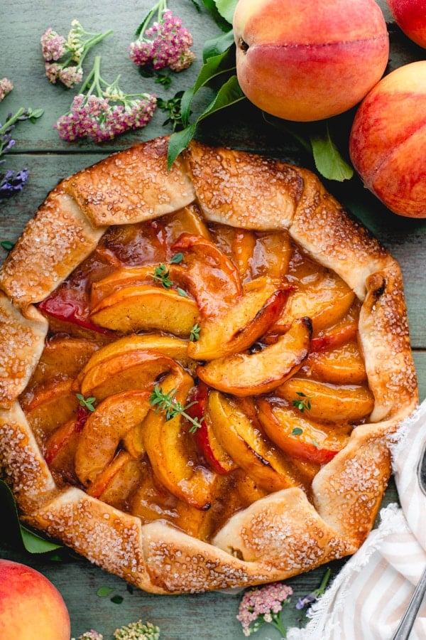 Overhead image of a spiced rustic peach galette on a green wooden table