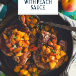 Overhead shot of pork chops with peach sauce in a cast iron skillet with text title overlay