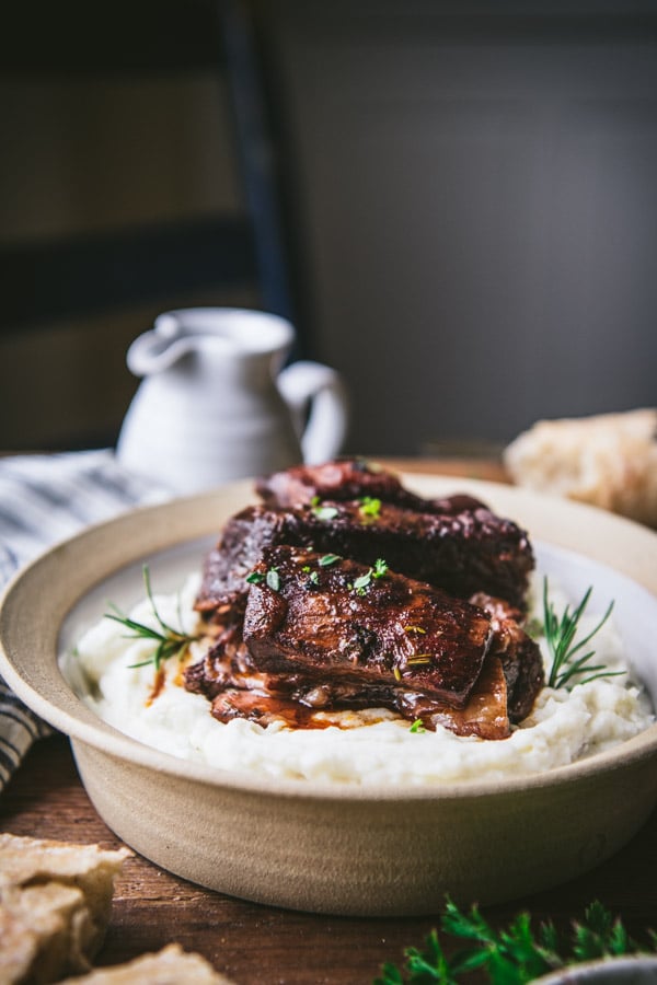 Tender red wine braised beef short ribs served atop of bed of mashed potatoes and topped with a red wine sauce and fresh rosemary.