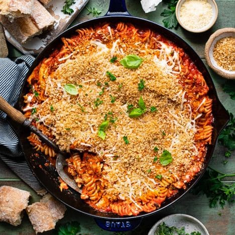 Close overhead square shot of a pan of shredded chicken parmesan casserole.