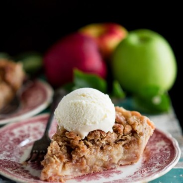 Side shot of a slice of apple pie with crumb topping on a plate