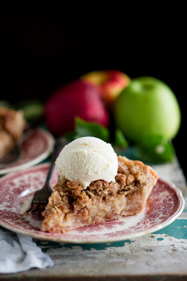 Side shot of a slice of apple pie with crumb topping on a plate