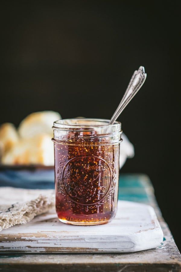 Side shot of a jar of old fashioned fig preserves with a spoon inside
