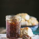 Close up side shot of a jar of homemade old fashioned fig preserves with warm biscuits