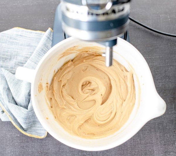 An overhead shot of the creamy no-bake peanut butter pie filling in a white stand mixer bowl.