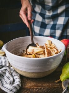 Stirring together pears and warm spices in a white bowl