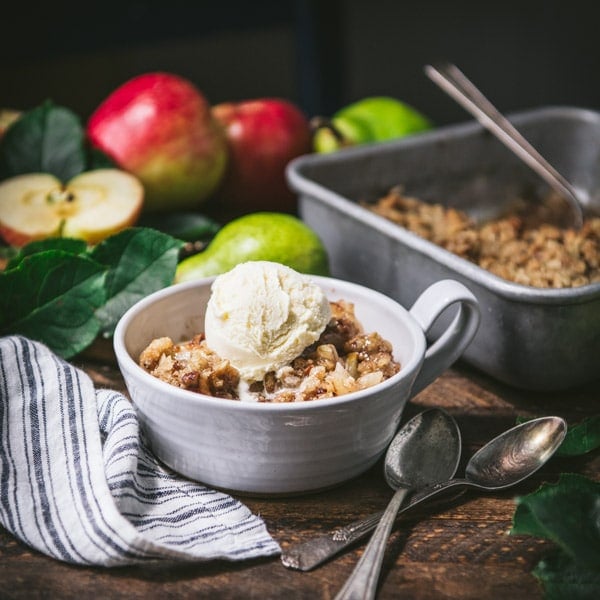 Square shot of a bowl of apple pear crisp on a wooden table