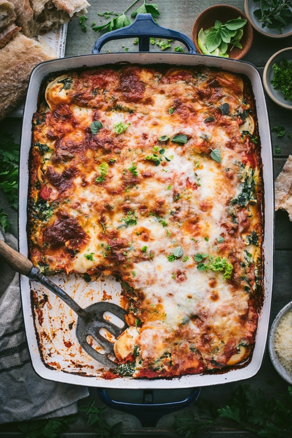 Overhead shot of a pan of easy ravioli lasagna with ricotta and spinach and serving spoon