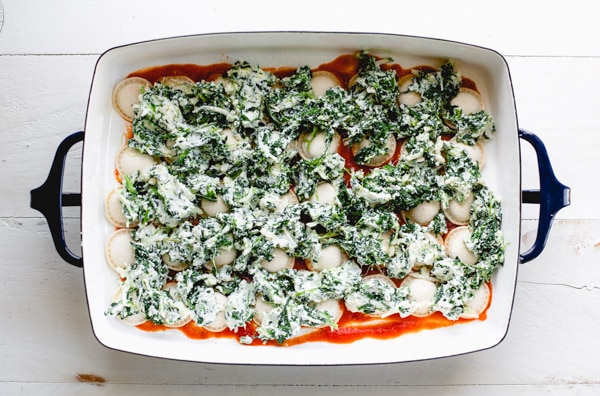 Frozen cheese ravioli in a pan with marinara and spinach ricotta mixture