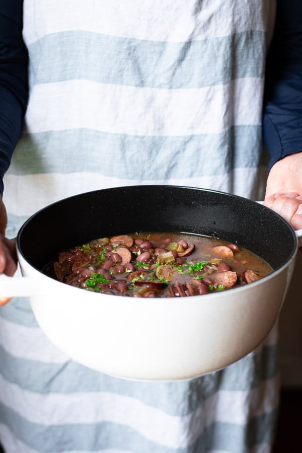 Hands holding a Dutch oven full of the best red beans and rice recipe