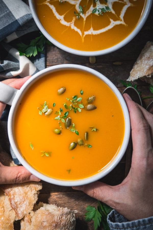 Hands holding a bowl of roasted butternut squash soup