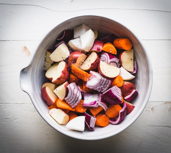Bowl of chopped raw carrots onions potatoes and turnips