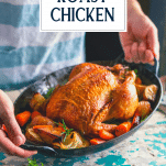 Hands holding a pan of oven roasted whole chicken with text title overlay