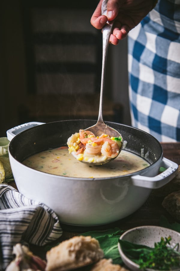 Ladle scooping up shrimp soup from a white pot
