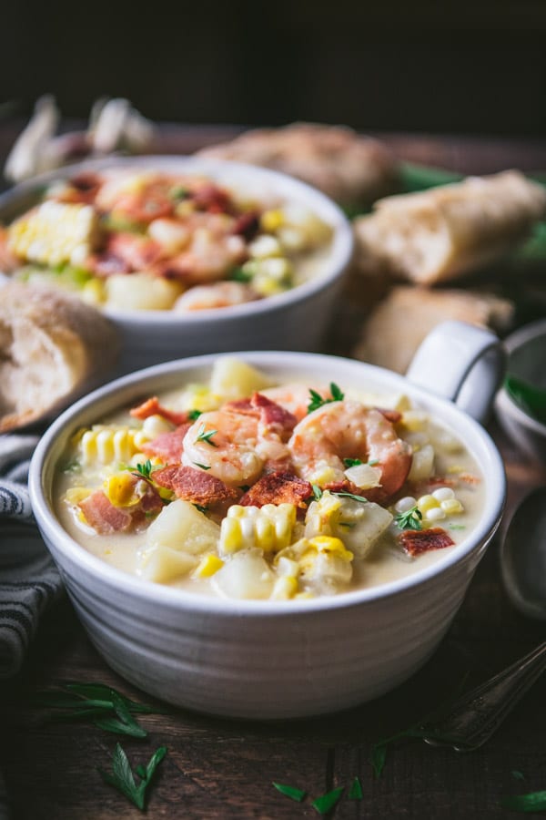 Side shot of a bowl of shrimp soup with corn