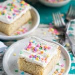 Slice of the best vanilla cake recipe on a white plate with sprinkles