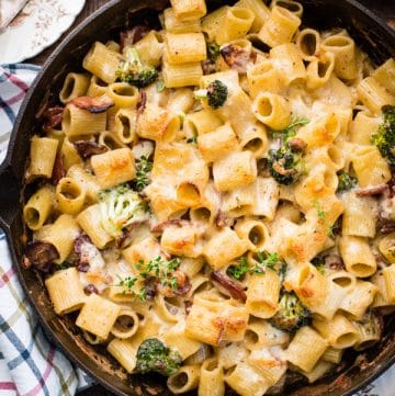Cheesy pasta bake with bacon and broccoli in a cast iron skillet