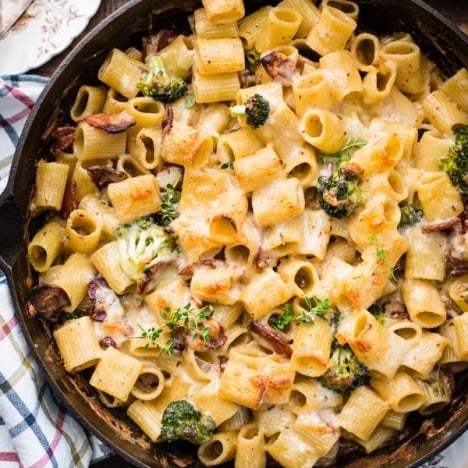 Cheesy pasta bake with bacon and broccoli in a cast iron skillet