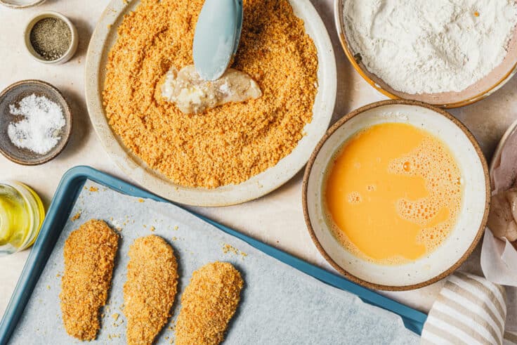 Process shot showing how to dredge chicken tenders in breading.