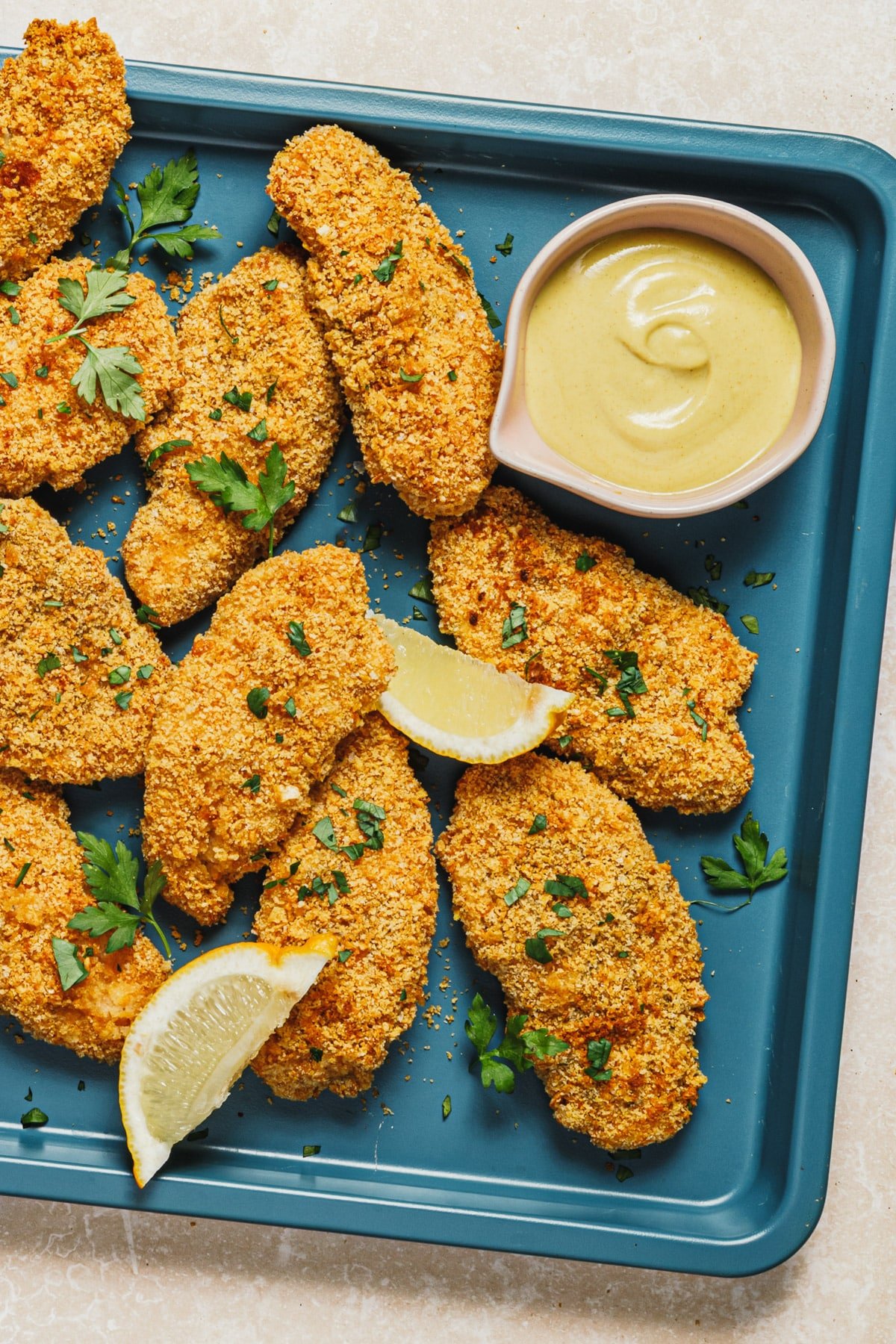 Overhead image of crispy baked breaded chicken tenders on a turquoise tray.