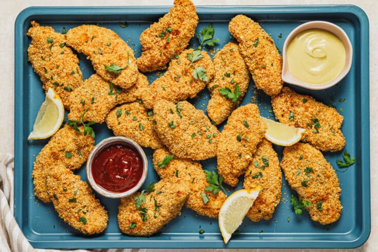 Horizontal overhead shot of a pan of baked chicken tenders.